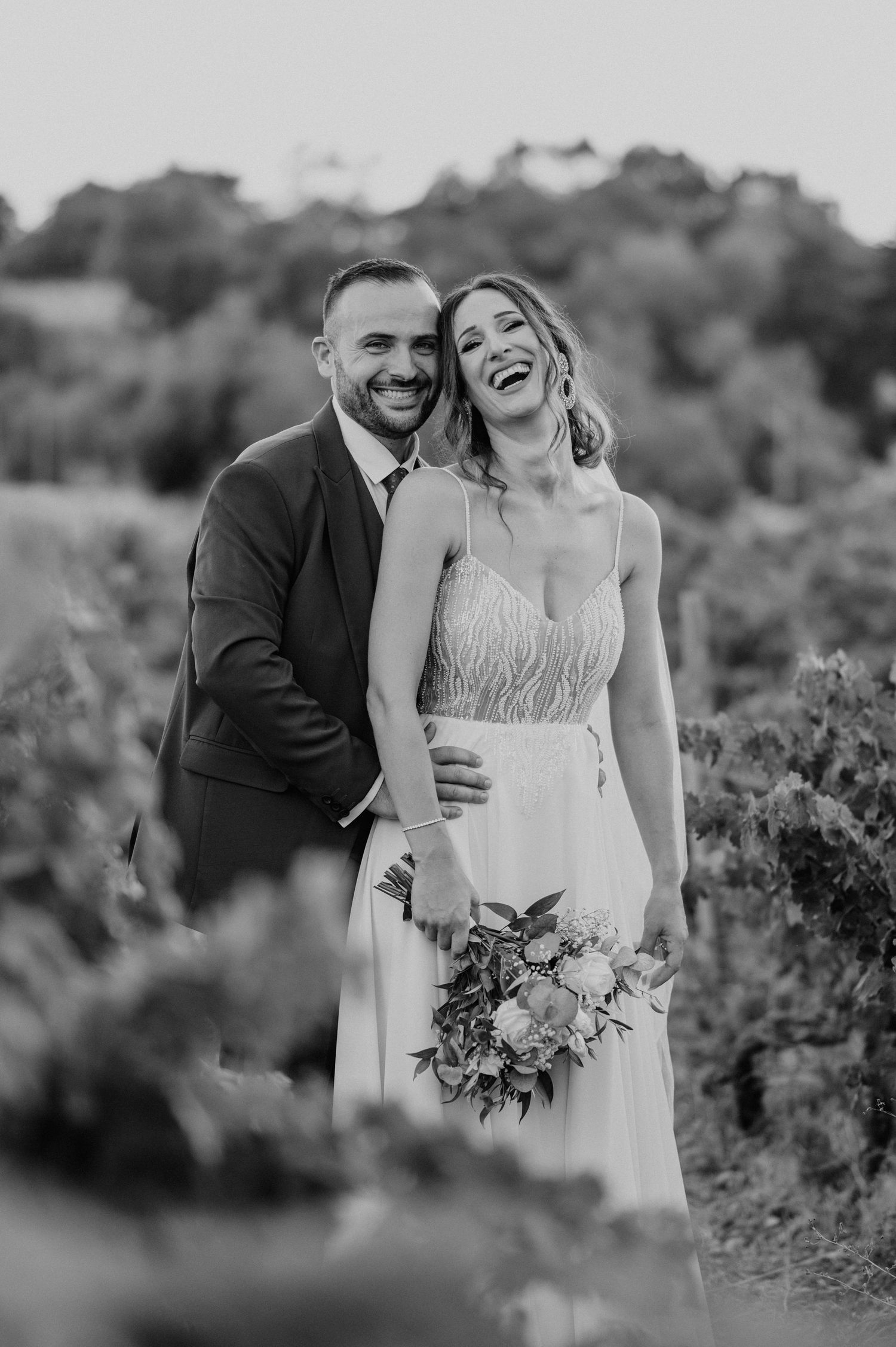 Black and white candid wedding photos showing joyful moments between a couple in a vineyard setting.