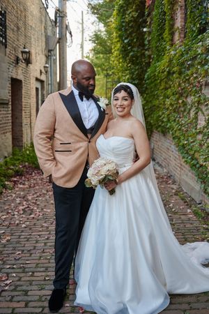 Newlyweds share a romantic moment on a brick-lined alley with ivy covered walls during their wedding photoshoot.