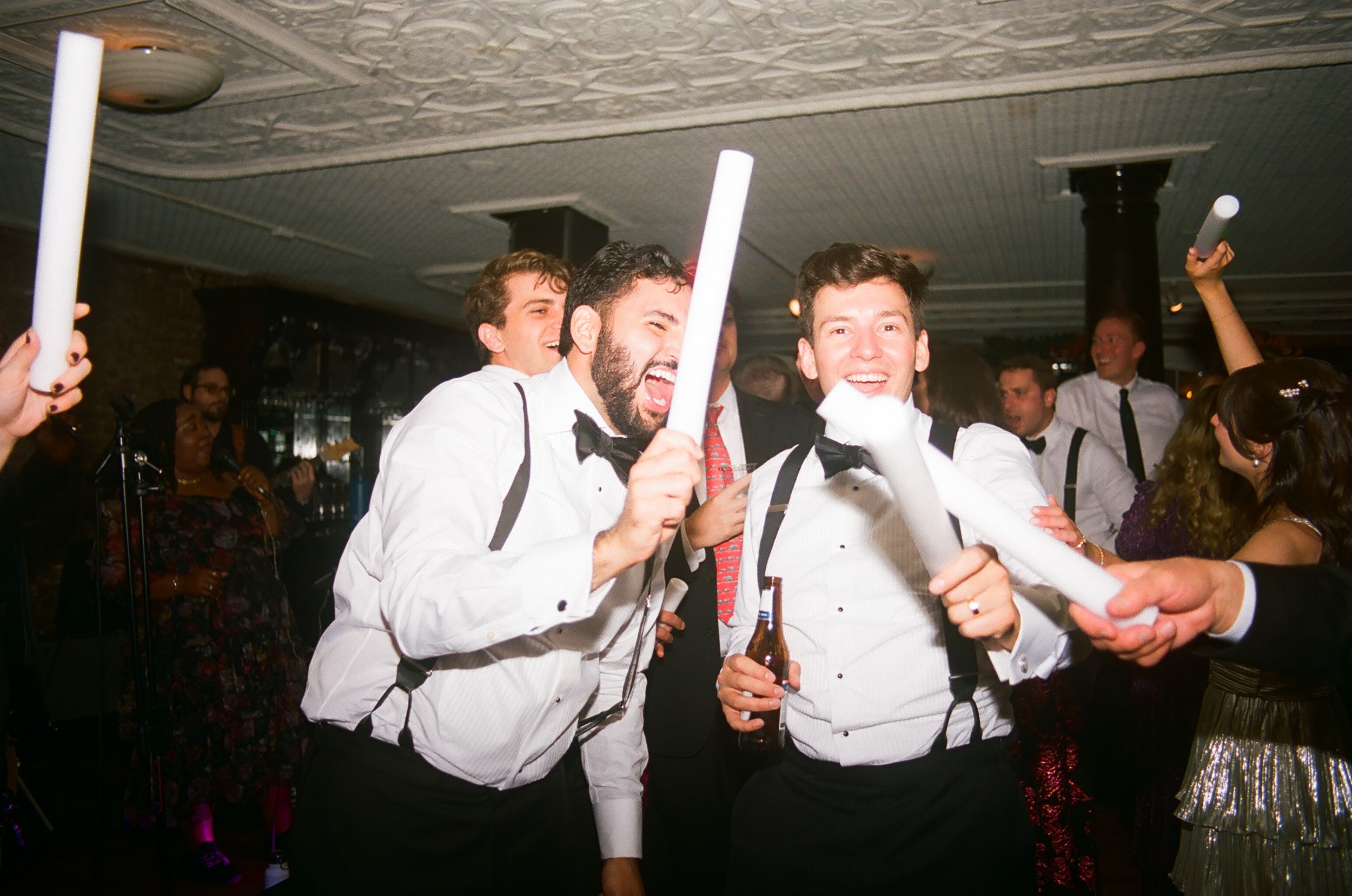 People in white shirts dancing and celebrating at a lively party with disco lights and decorations.
