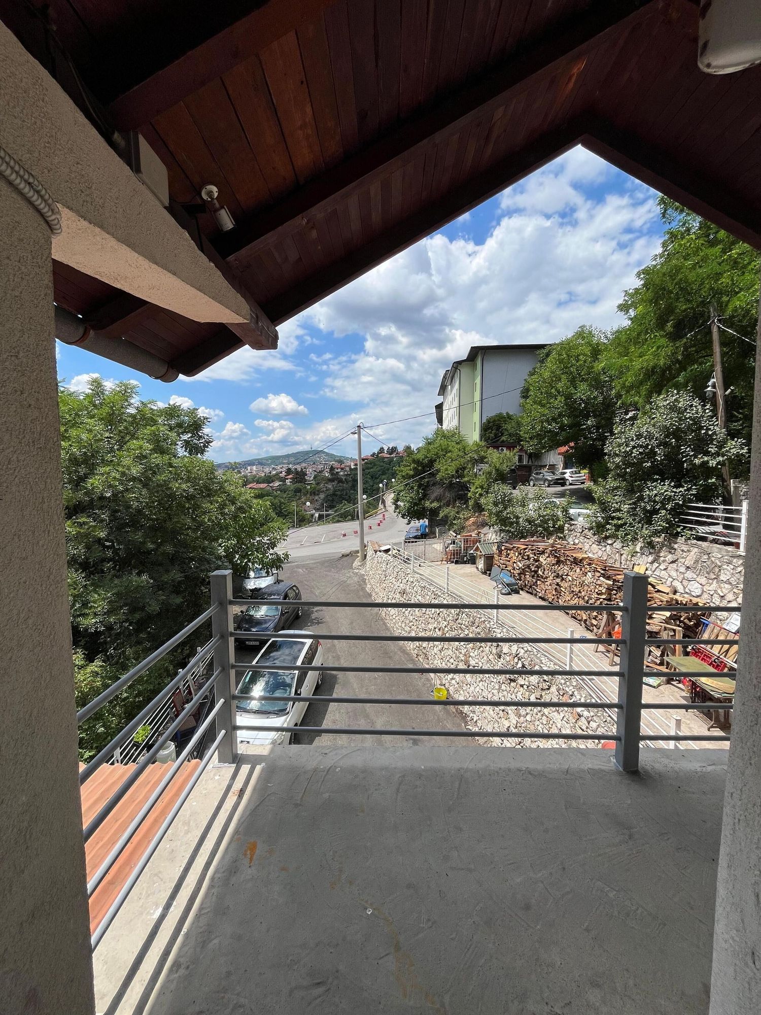 View from a covered deck overlooking a residential street with mountains and blue skies in the background.