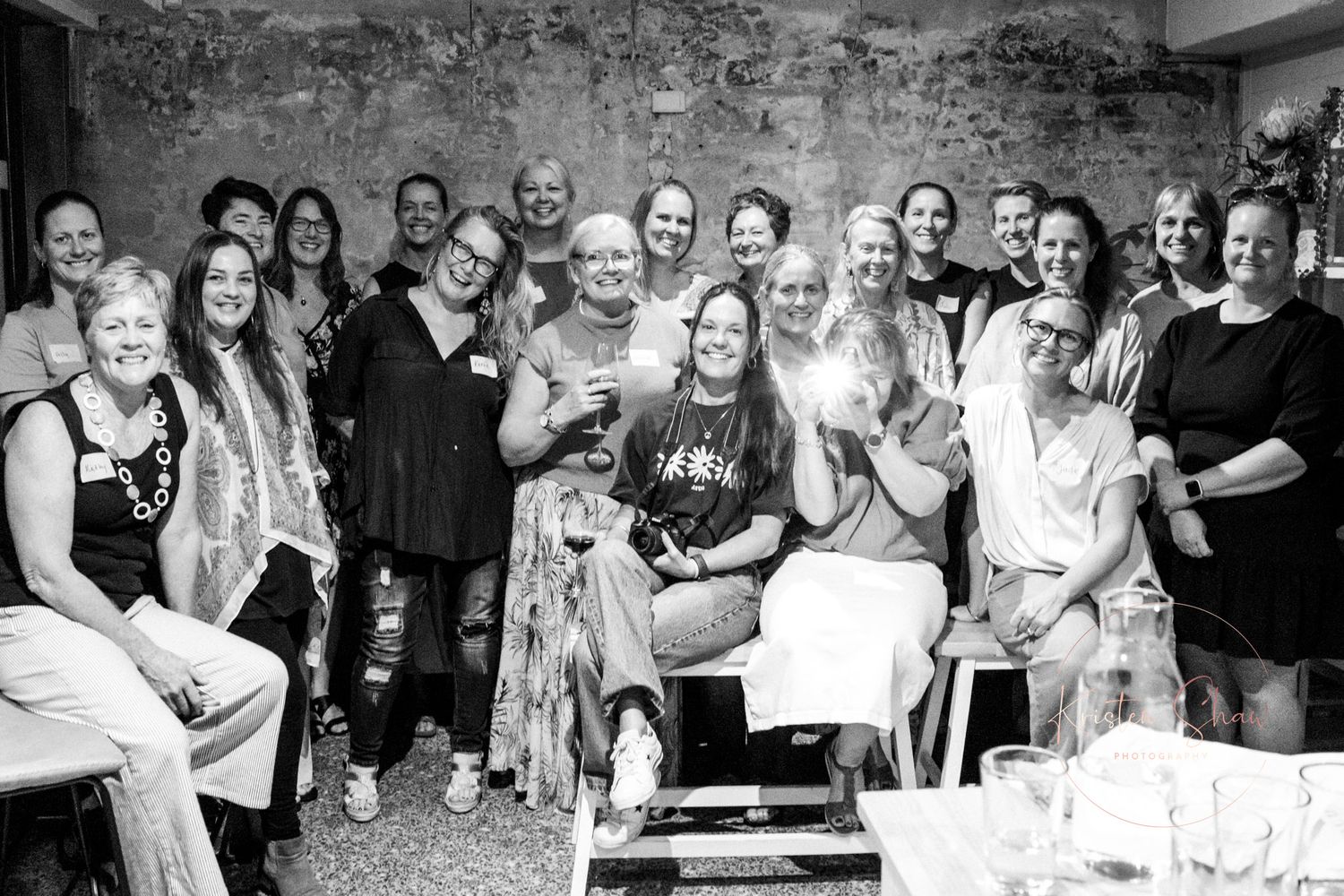 Black and white group photo of smiling women gathered together at an indoor social event or celebration.