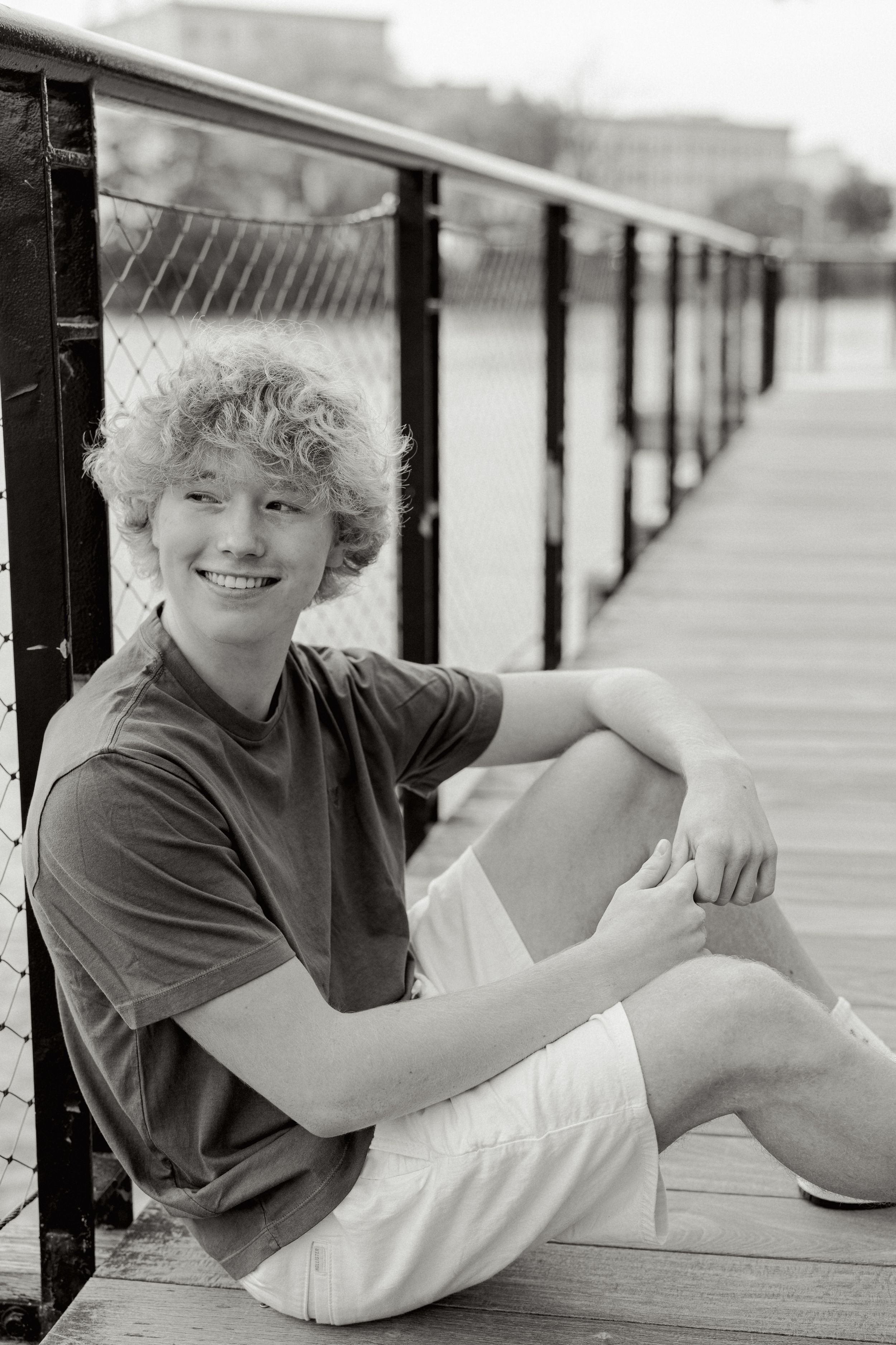 Black and white portrait on wooden deck with metal railing.