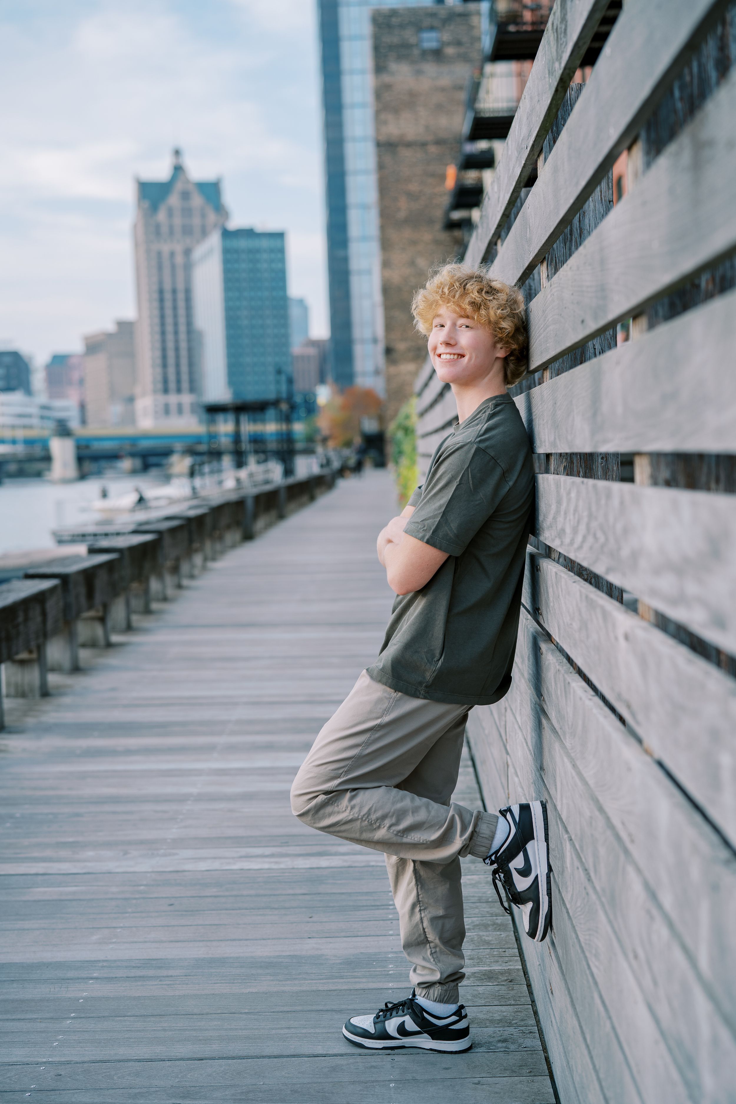 Urban photoshoot showing casual poses against concrete wall with city skyline in background.