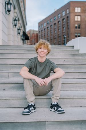 Casual outdoor portrait session on concrete steps with brick building backdrop.