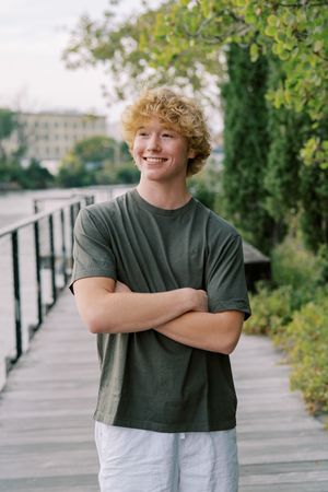 Casual outdoor portrait in olive green t-shirt and white shorts on walkway.