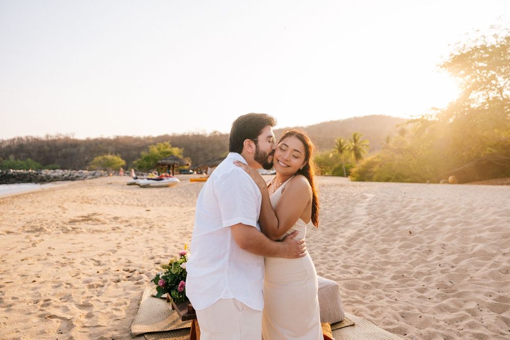 A couple embraces on a sandy beach at sunset during a romantic photoshoot in Hawaii.