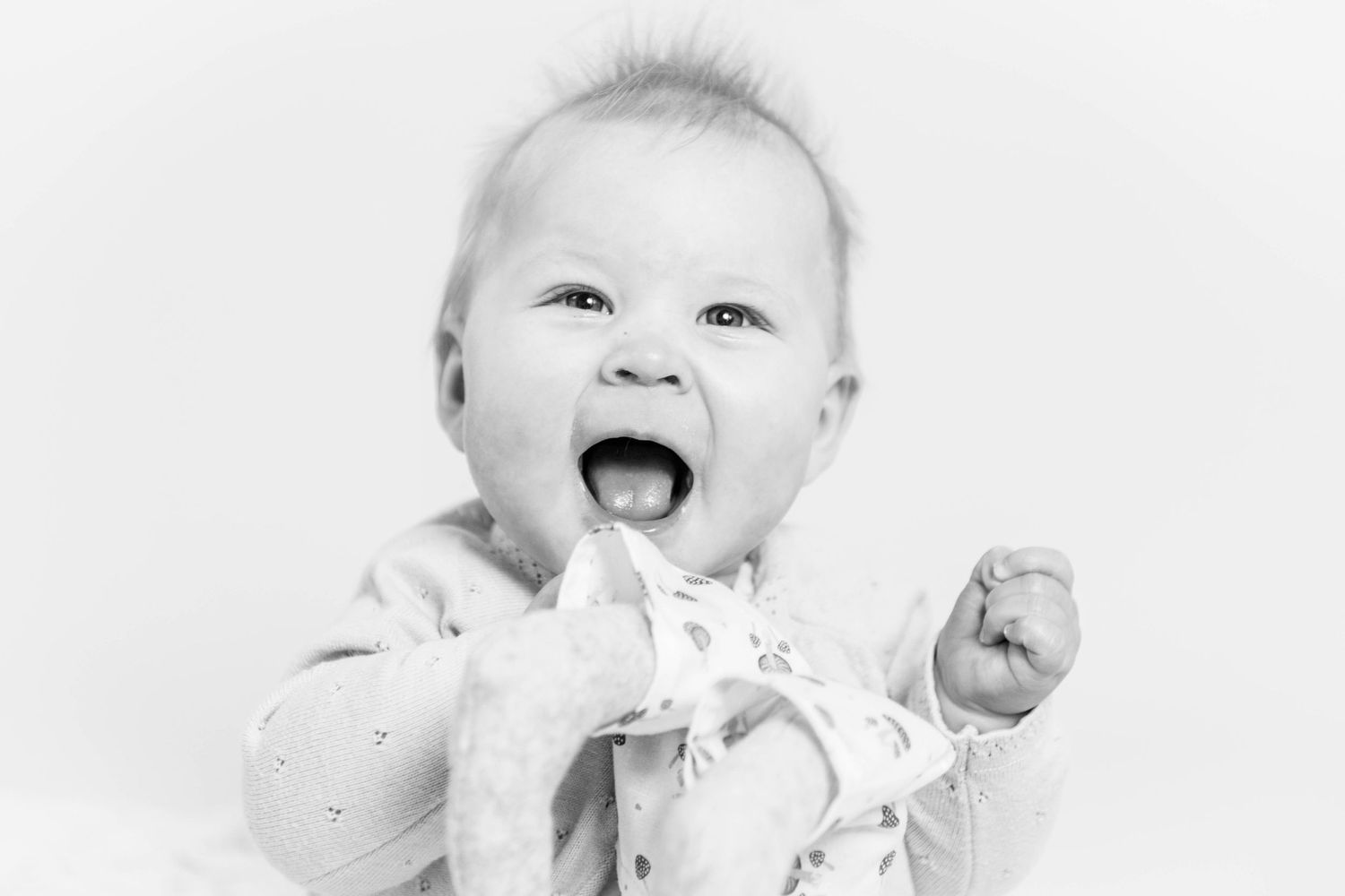 Happy baby laughing and clapping hands in black and white portrait photo.