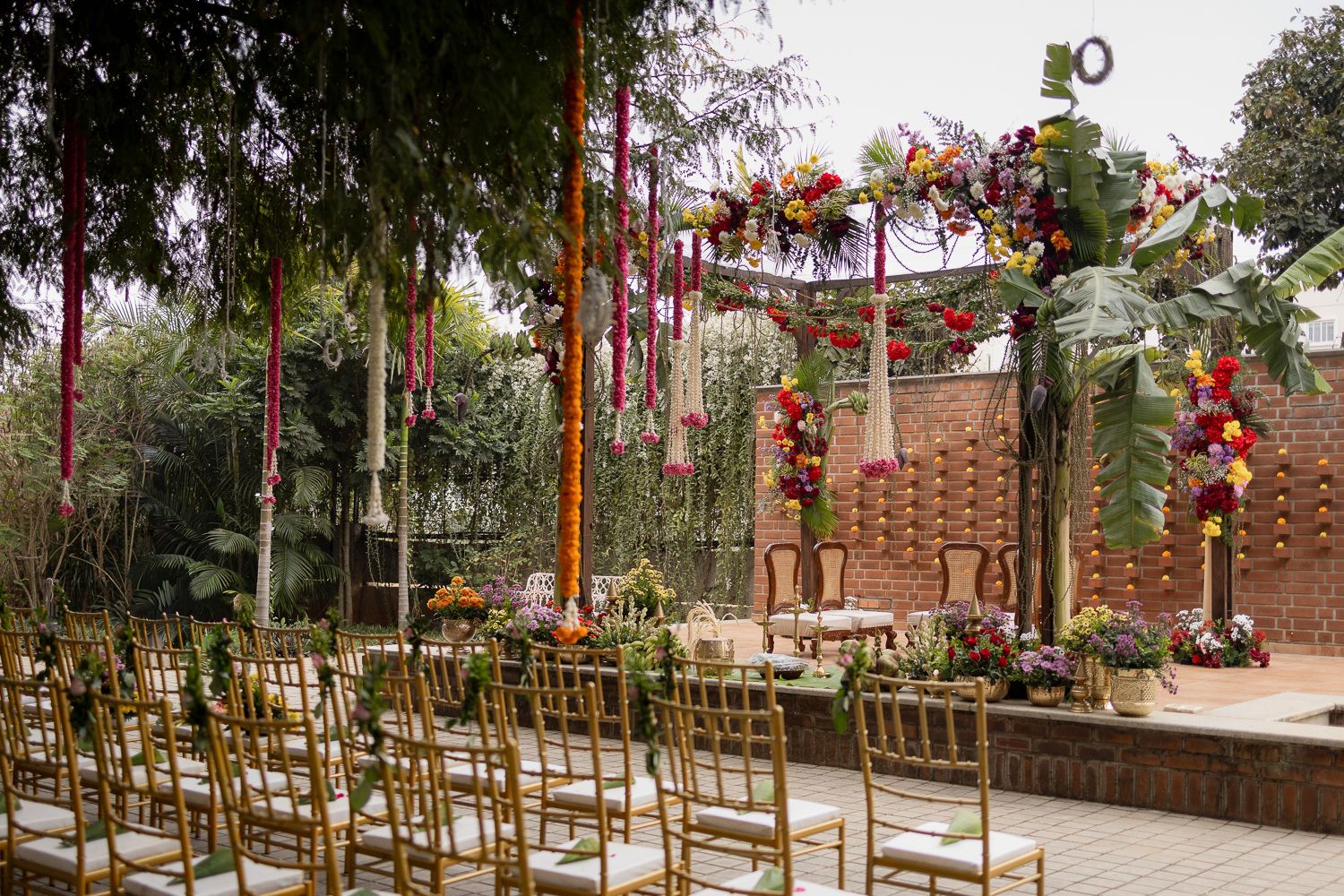 Outdoor wedding ceremony setup with wooden chairs and floral decorations along a rustic aisle path.