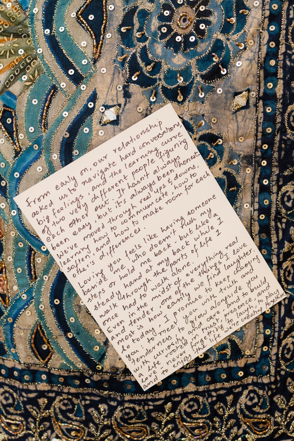 Handwritten note on a blue and gold patterned fabric background with ornate decorative swirls and dots.