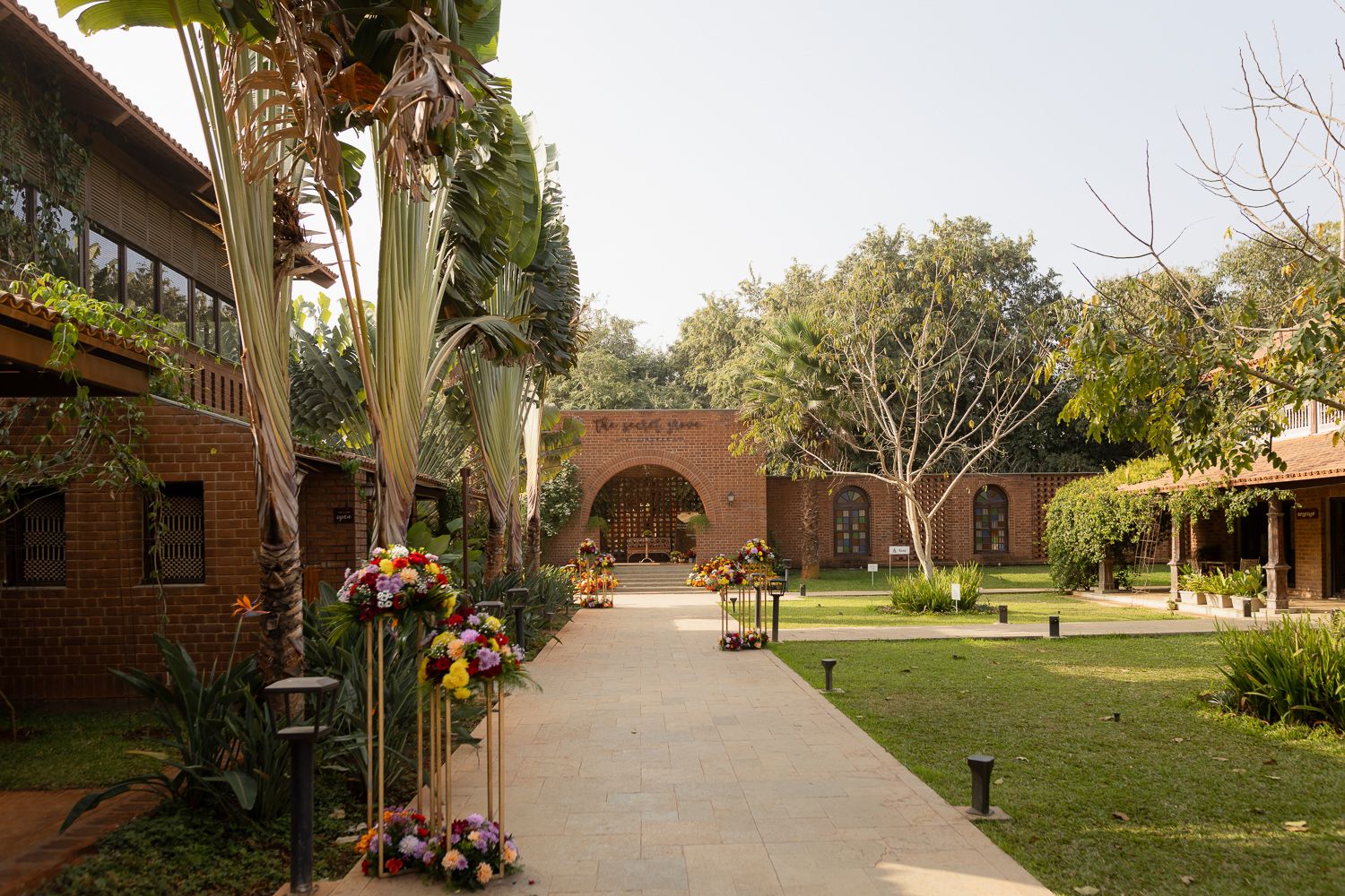 Tree-lined walkway with brick buildings and lampposts along a college campus path in autumn.