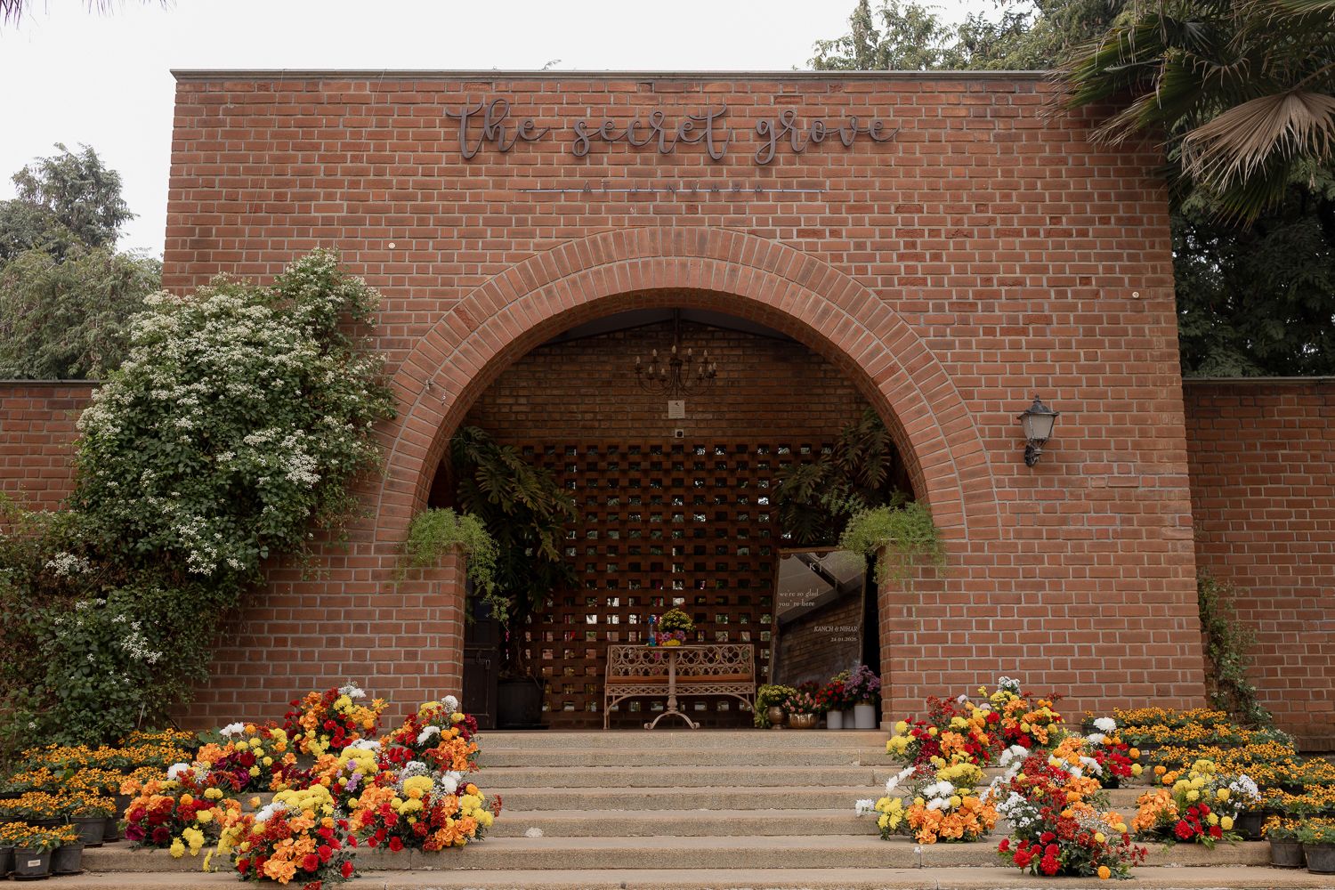 Fall pumpkins and colorful floral arrangements decorate the steps of a red brick building entrance.
