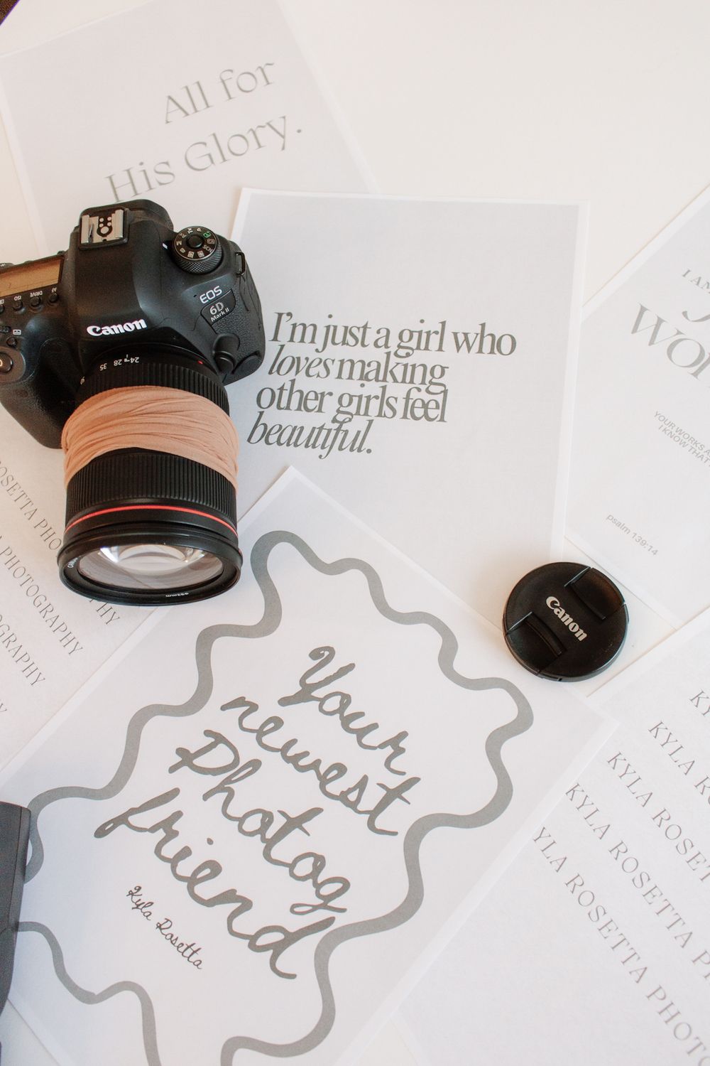 A series of Canon DSLR cameras and lenses arranged on white paper with handwritten text and decorative elements.