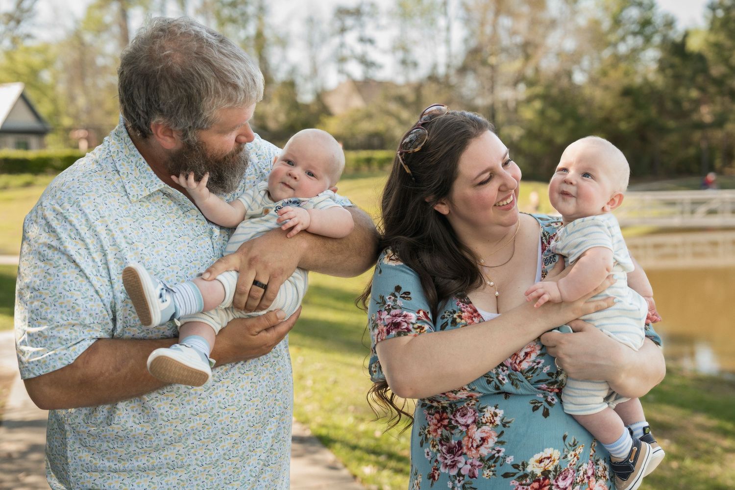 A loving family shares tender moments together outdoors during a photo session in a sunlit park setting.