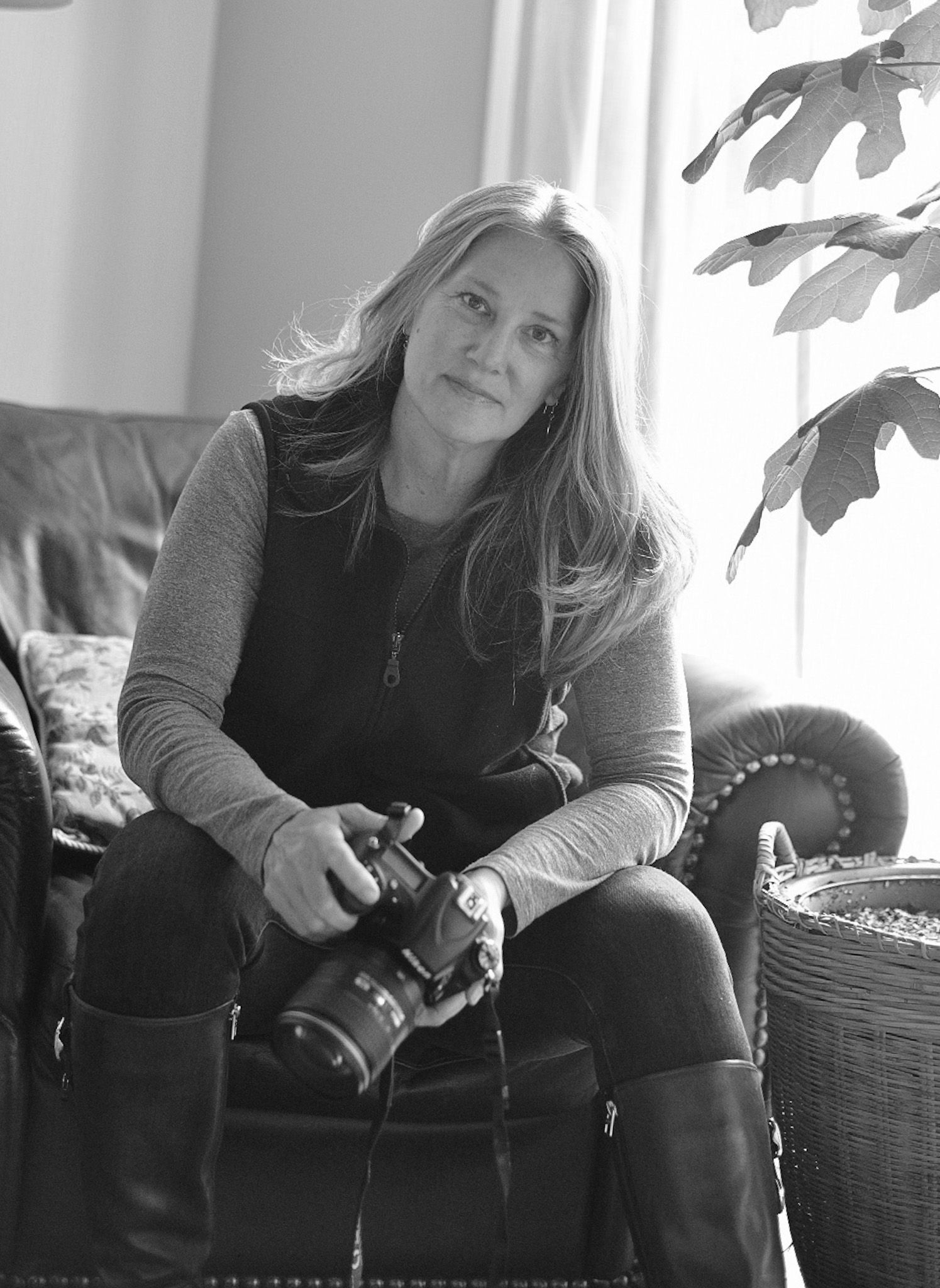 Black and white portrait of someone with camera equipment in natural window light.