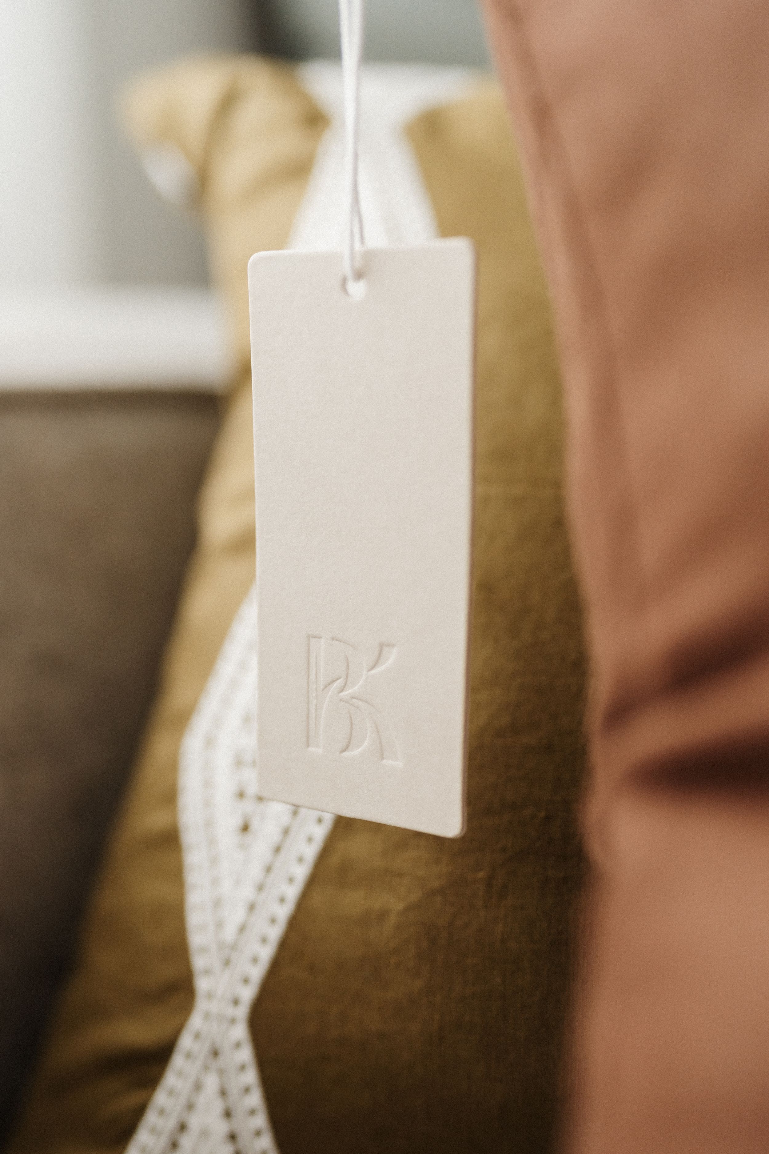 Close-up view of white hanging retail tags with delicate designs against a brown background.