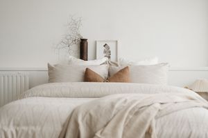 A cozy white bedding set with fluffy pillows and neutral tones creates a serene bedroom atmosphere.