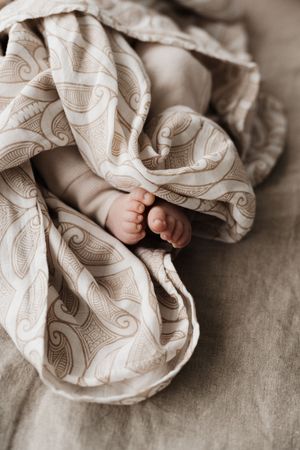 Close-up of tiny baby feet nestled in soft patterned blanket.