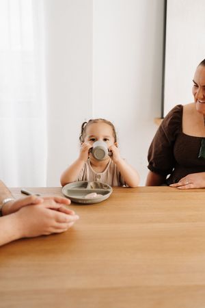 A sequence of images showing someone drinking from a cup at a wooden table in warm lighting.