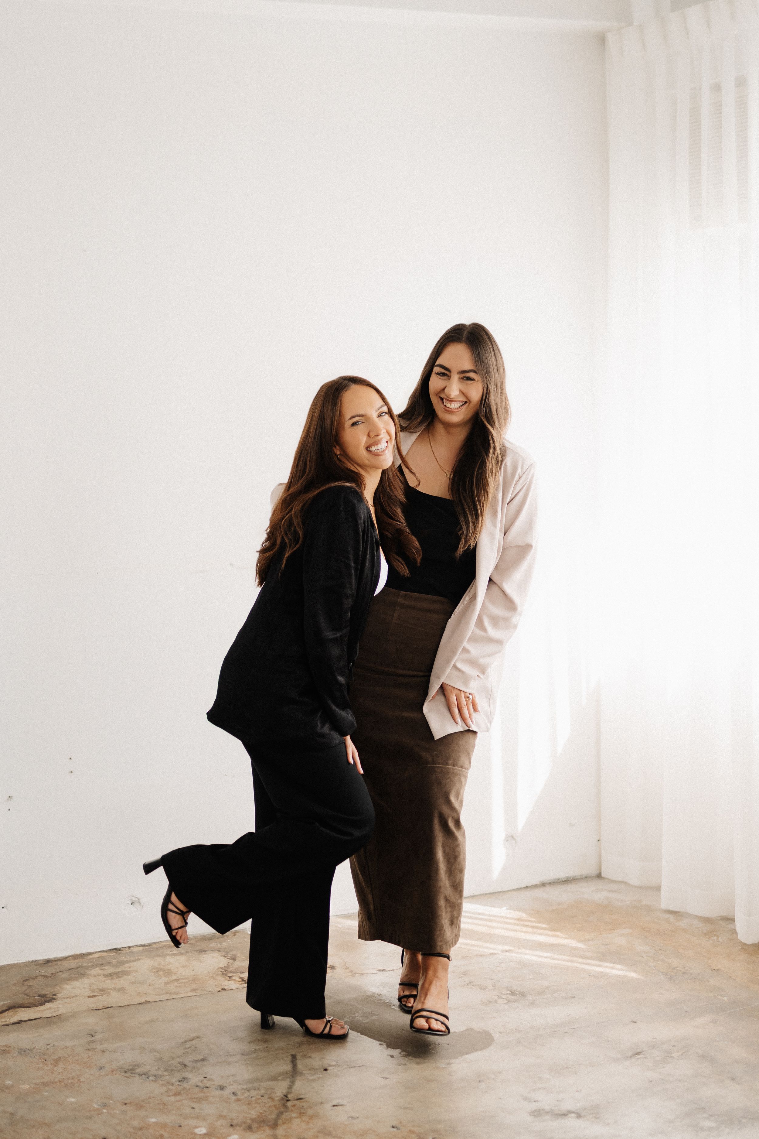 Two people share a candid moment in a bright minimalist room with white walls.