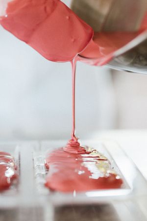 Pink liquid being poured onto a clear surface creating an artistic flow pattern.