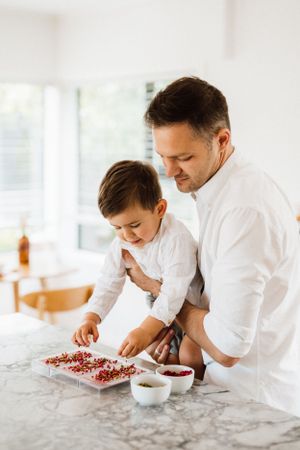 Two people in white chef coats prepare ingredients together on a marble counter.