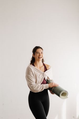 A series of photos showing a person in black pants and white top laughing and holding a yoga mat against a white backdrop.