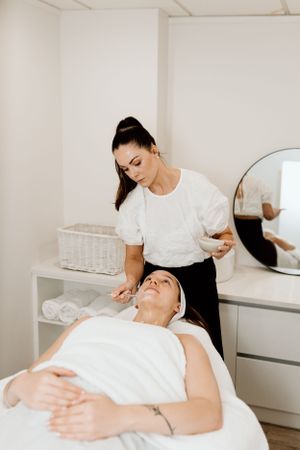 Professional esthetician performing a facial treatment on a client in a serene spa room.