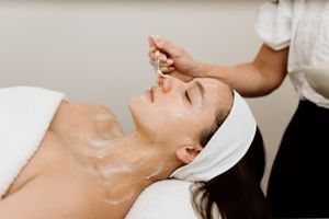 Spa technician removing a facial treatment mask in a professional setting.