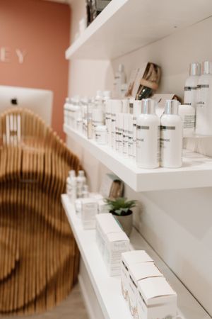 Clean white shelves displaying luxury skincare products in a modern spa retail setting.