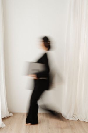 Artistic motion blur portrait in black against white curtains.