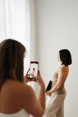 Behind-the-scenes photo shoot with photographer capturing model in beige outfit.