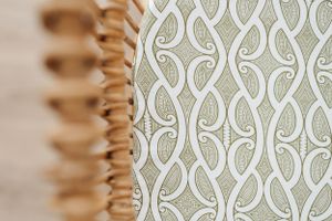 Detailed view of cream colored fabric with elegant swirling geometric pattern design.