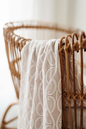 Close-up of decorative white lace fabric draped over rattan furniture with intricate pattern details.