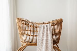 Vintage rattan chair with white decorative throw blanket in minimalist setting.