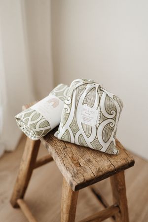 Decorative throw pillows with elegant swirl patterns displayed on rustic wooden stool.