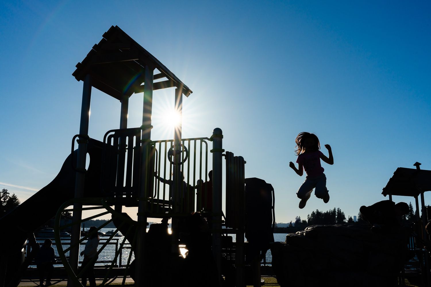 Silhouette photo of kid jumping on playground equipment.