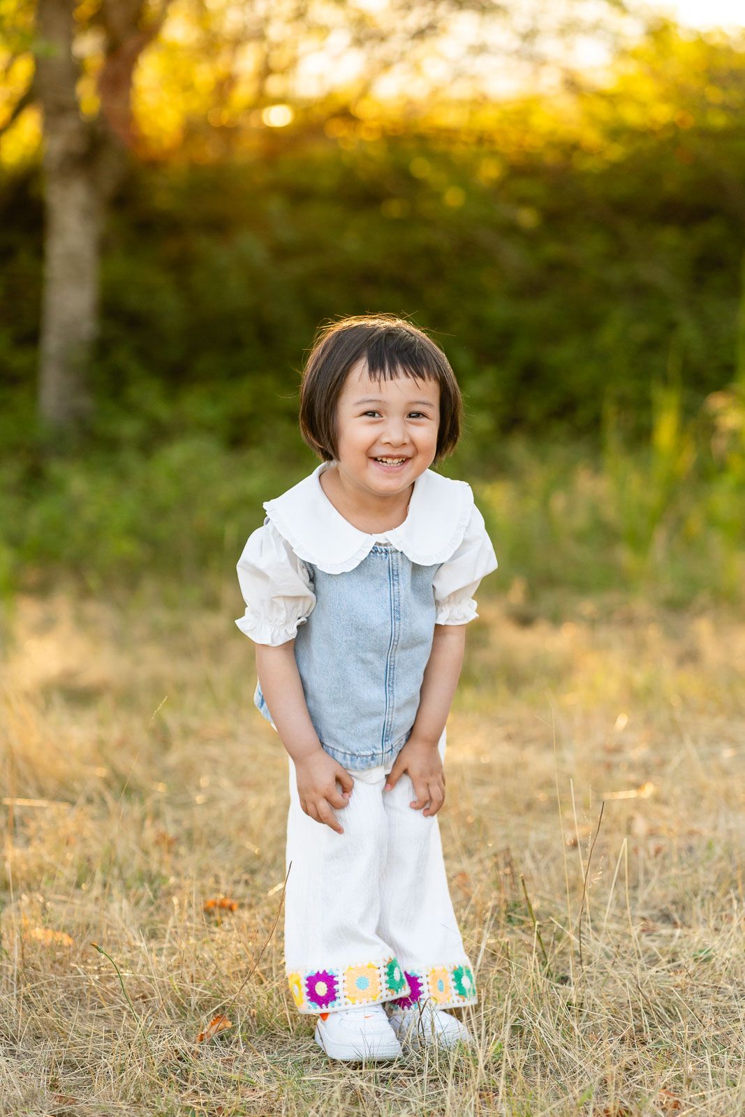 Little girl smiling at golden hour in a field.