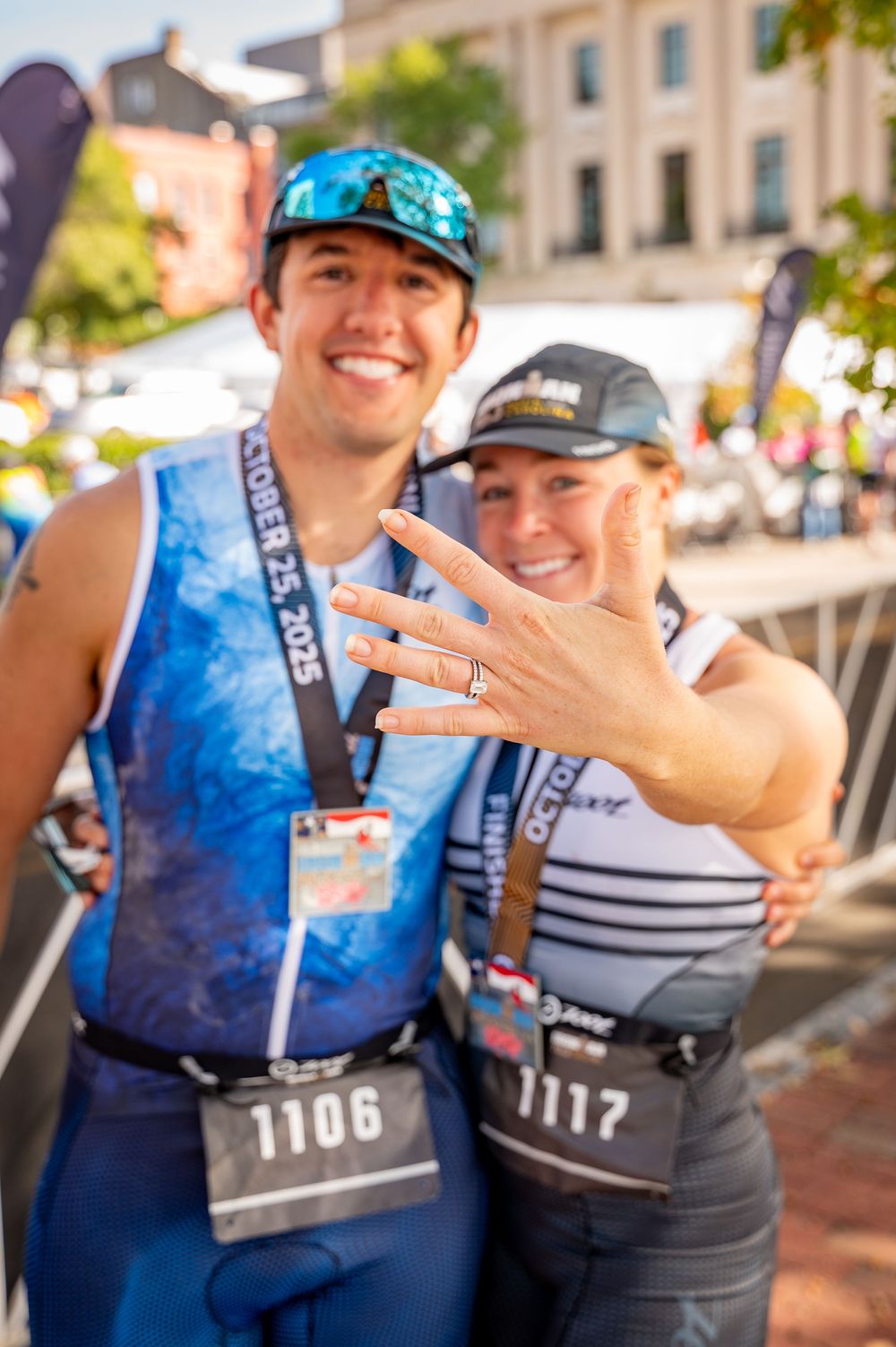 Two runners showing off their race bibs at an outdoor running event.
