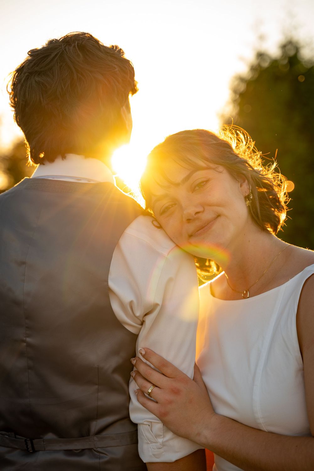 A couple shares an intimate moment in golden sunlight with a warm backlit glow.