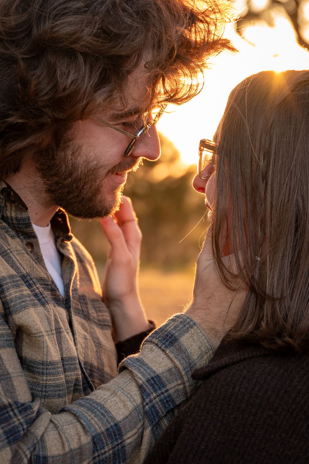 Intimate close-up silhouette of a couple sharing a tender moment in warm sunset lighting.