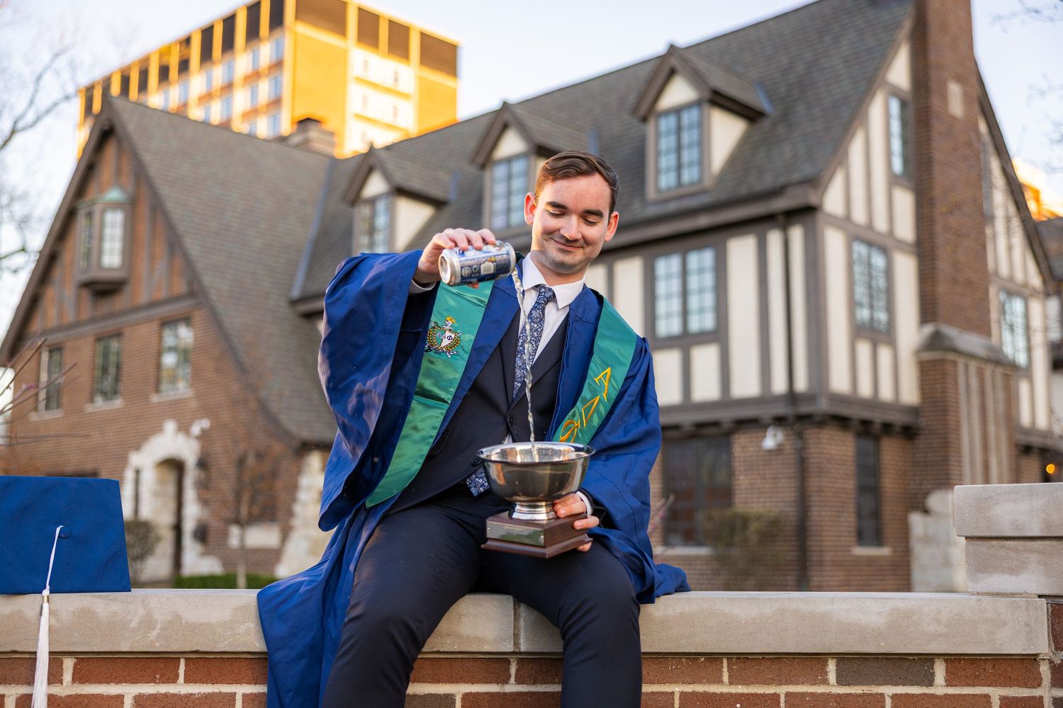 A graduating student at UIUC pouring a drink into a trophy to celebrate graduation