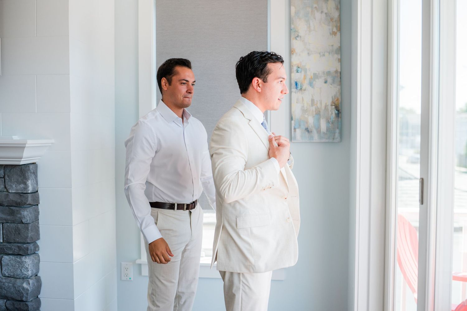 Two people in white shirts stand near a window in a modern interior space.
