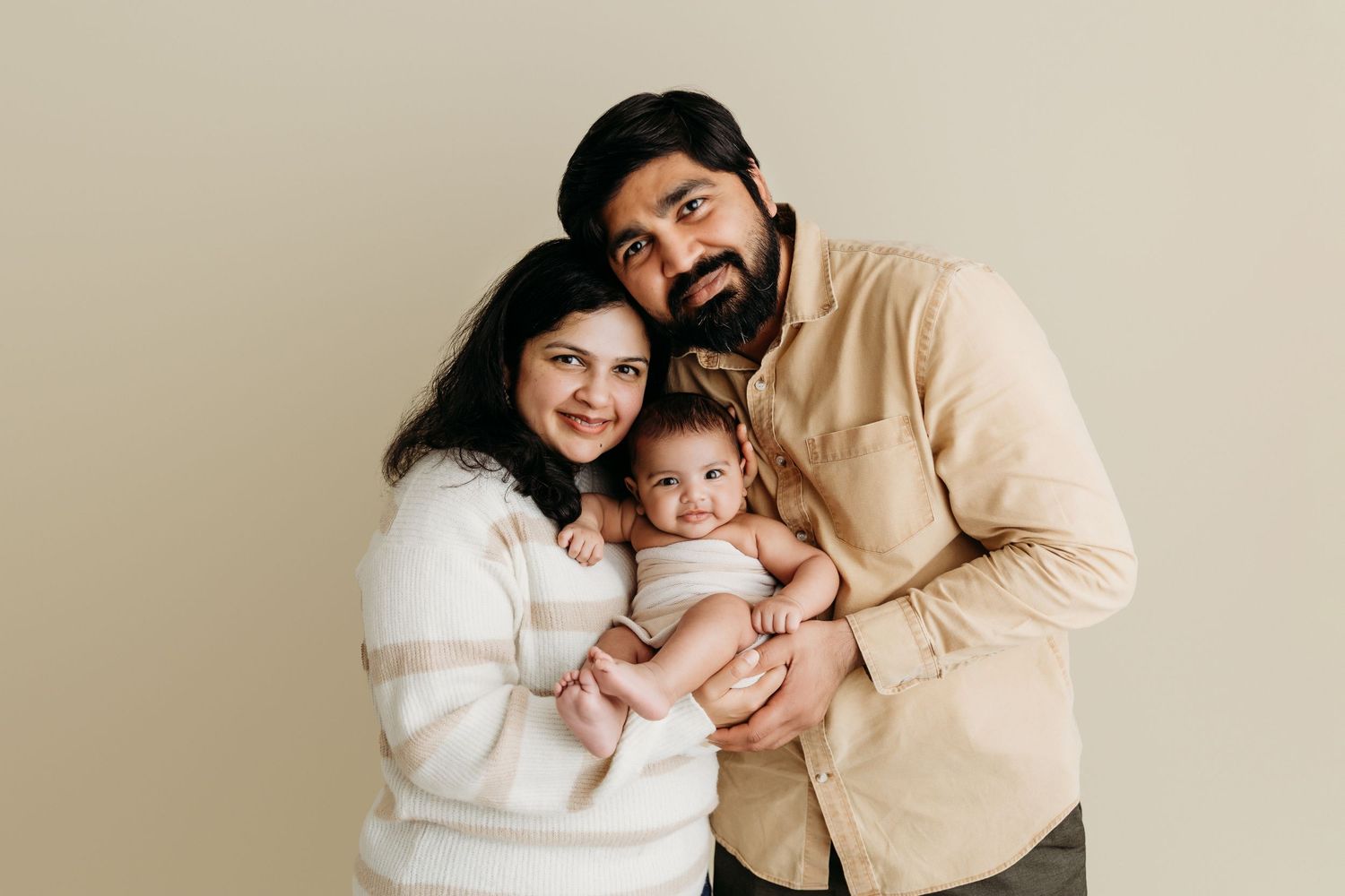 A loving family in cream and white outfits poses together for a warm and intimate photoshoot.