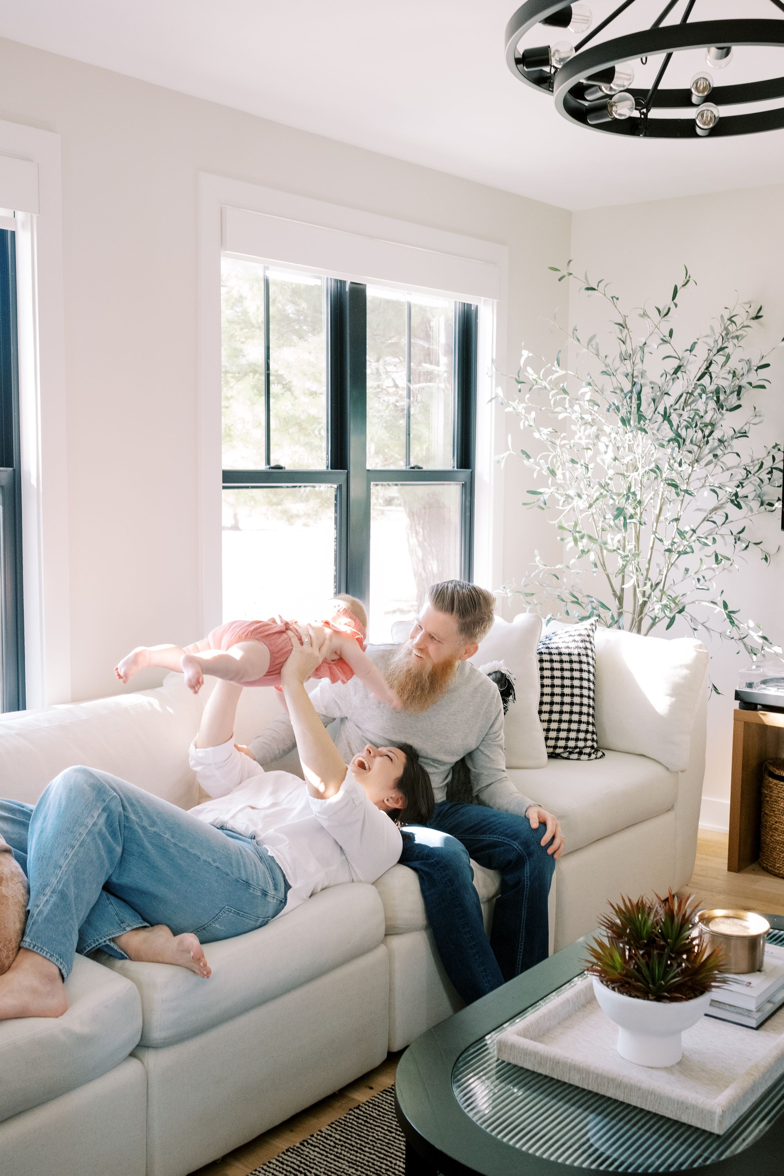 Person lounging comfortably on a white couch in a bright modern living room with decorative plants.