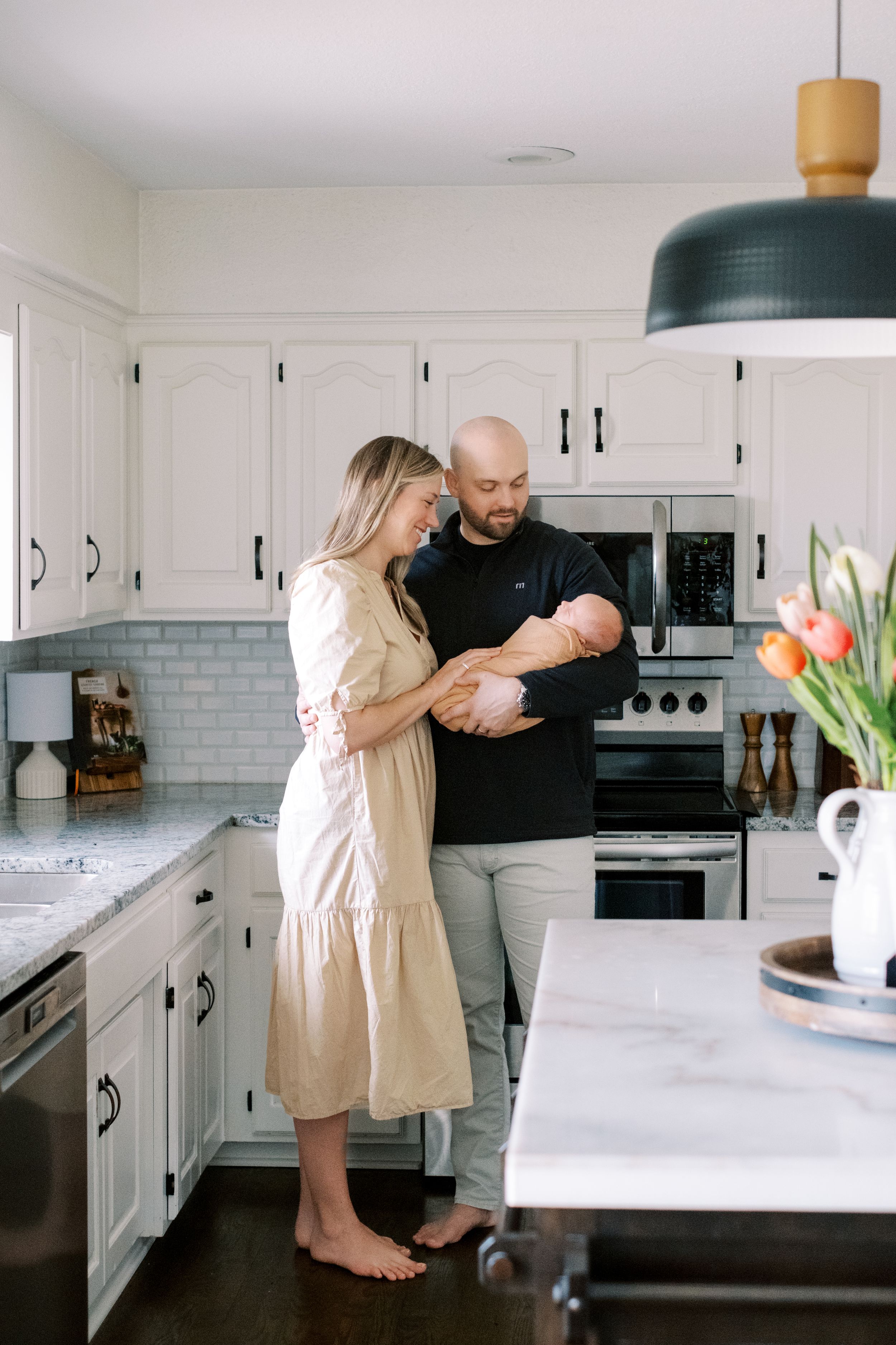 A couple shares tender moments together in their modern white kitchen with subway tile backsplash.