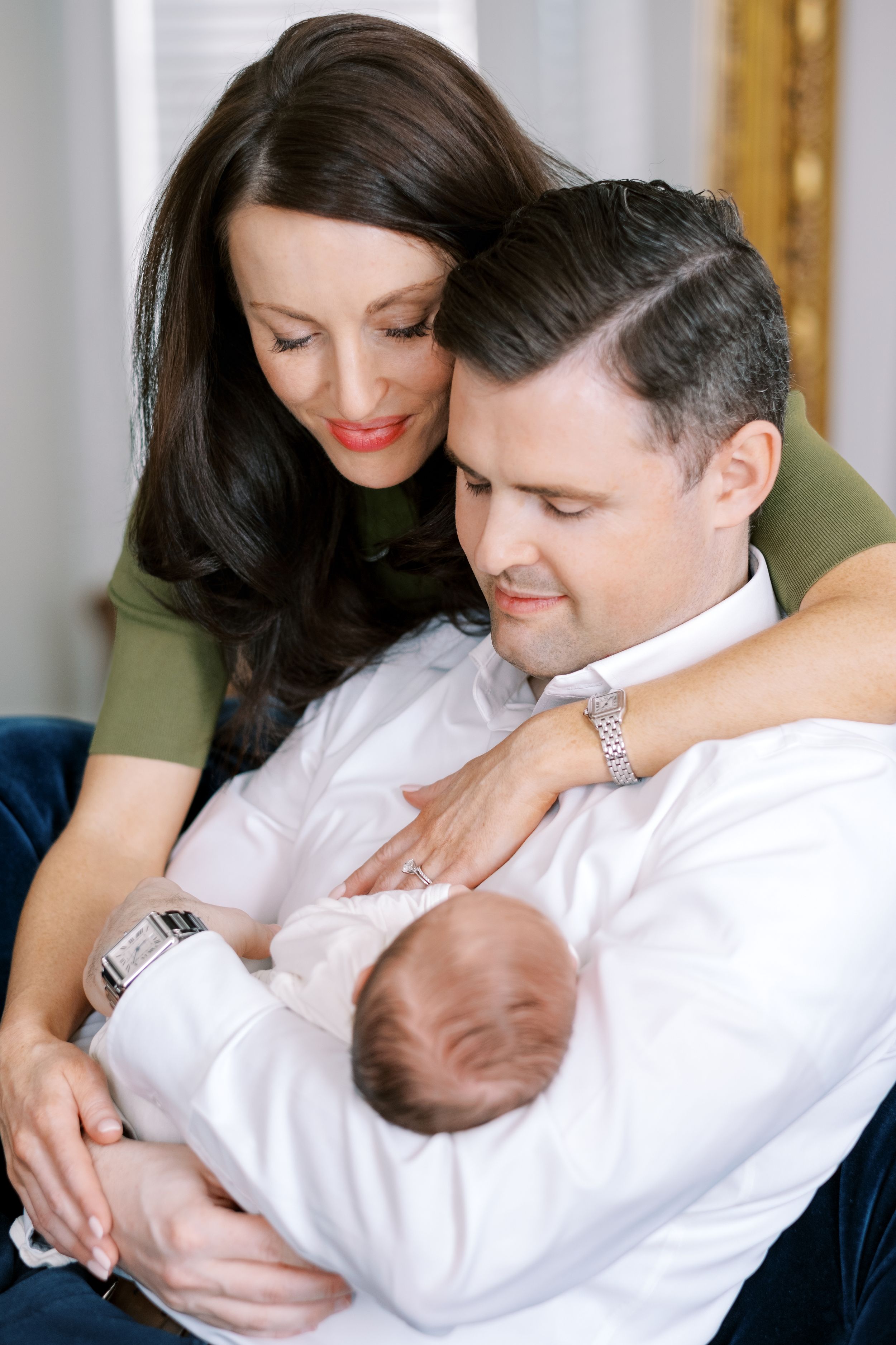 A series of intimate family photos showing parents bonding with their newborn baby in white clothing.