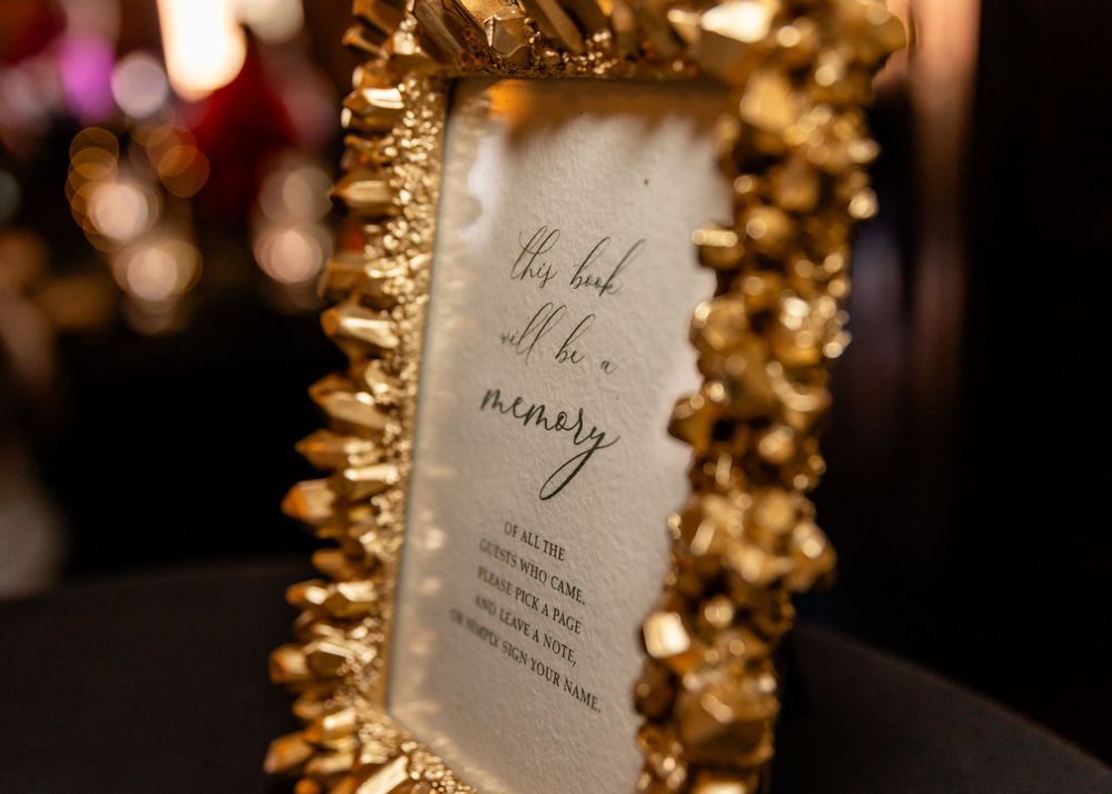 Elegant gold ornate picture frame with cursive script memory quote sign at a wedding reception.