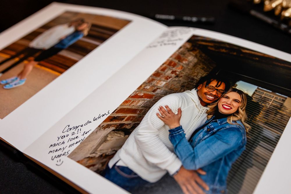 Open wedding photo album showing an engagement photo of a smiling couple with a handwritten congratulations note.