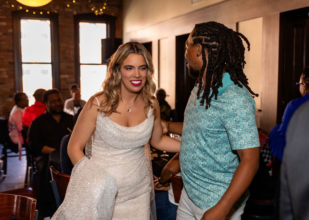 Woman in white sparkly dress smiling and chatting with a man in teal shirt at an indoor wedding  at Blue Sushi in Downtown Omaha, NE