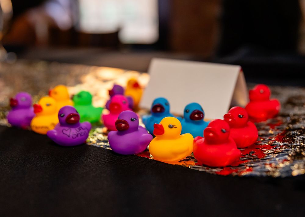 Colorful rubber ducks in rainbow colors arranged on a reflective surface at a wedding reception.